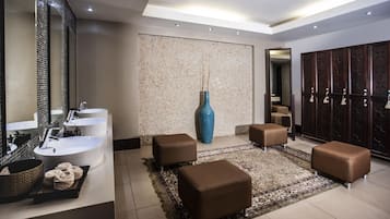Une salle de bain moderne avec deux vasques, un grand miroir, un vase bleu et un tapis à motifs.