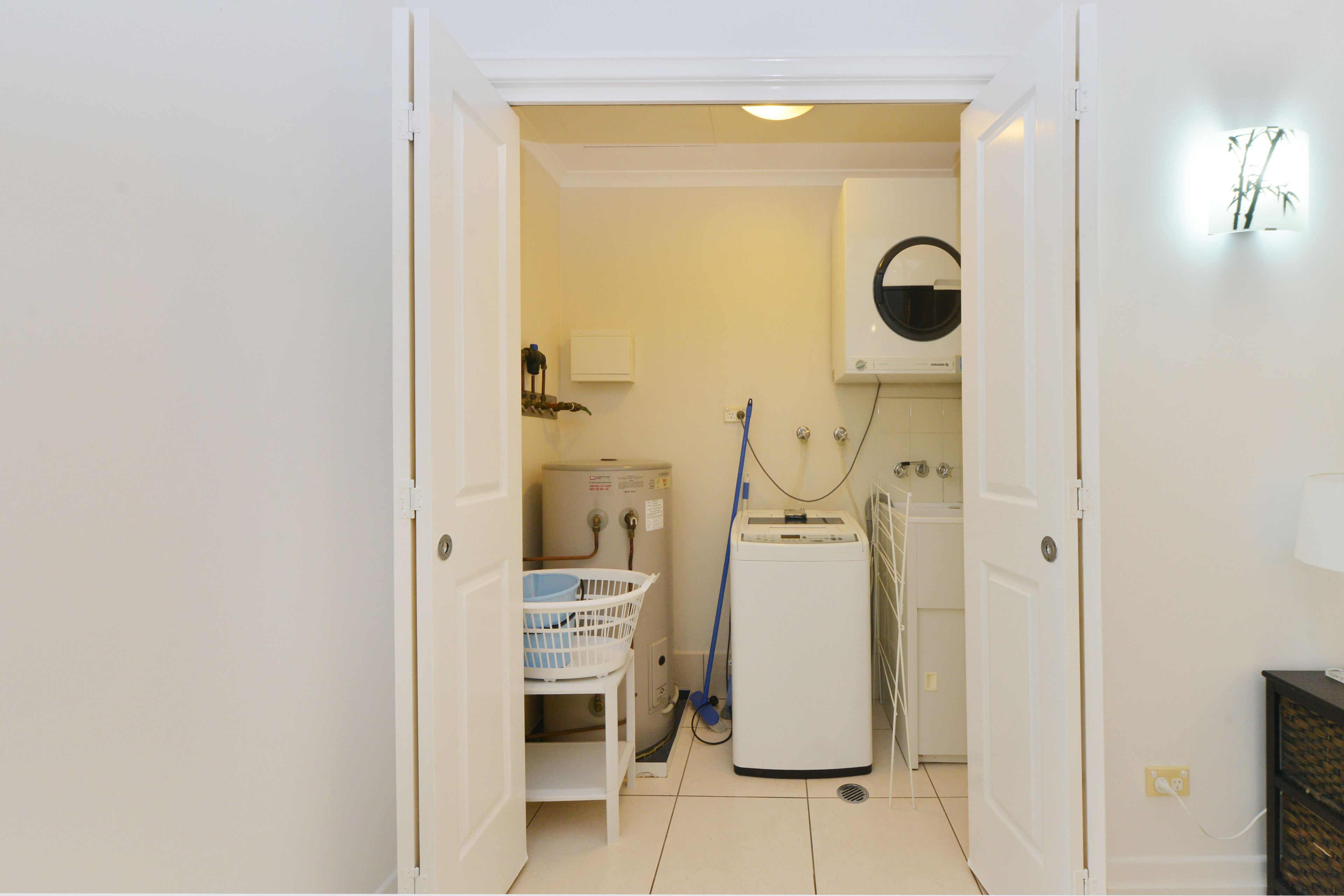 A laundry room with a washing machine, dryer, and a wall-mounted heater.