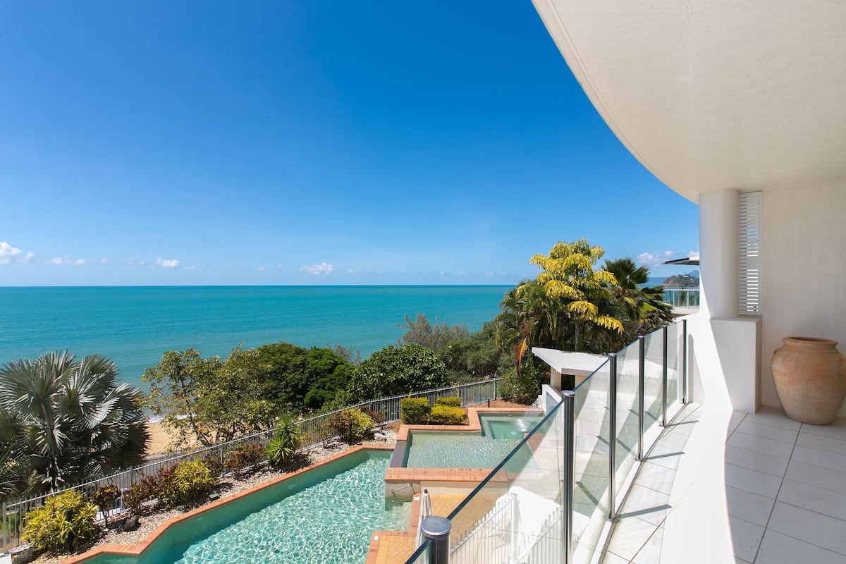 Un balcon avec vue sur une piscine et l’océan.