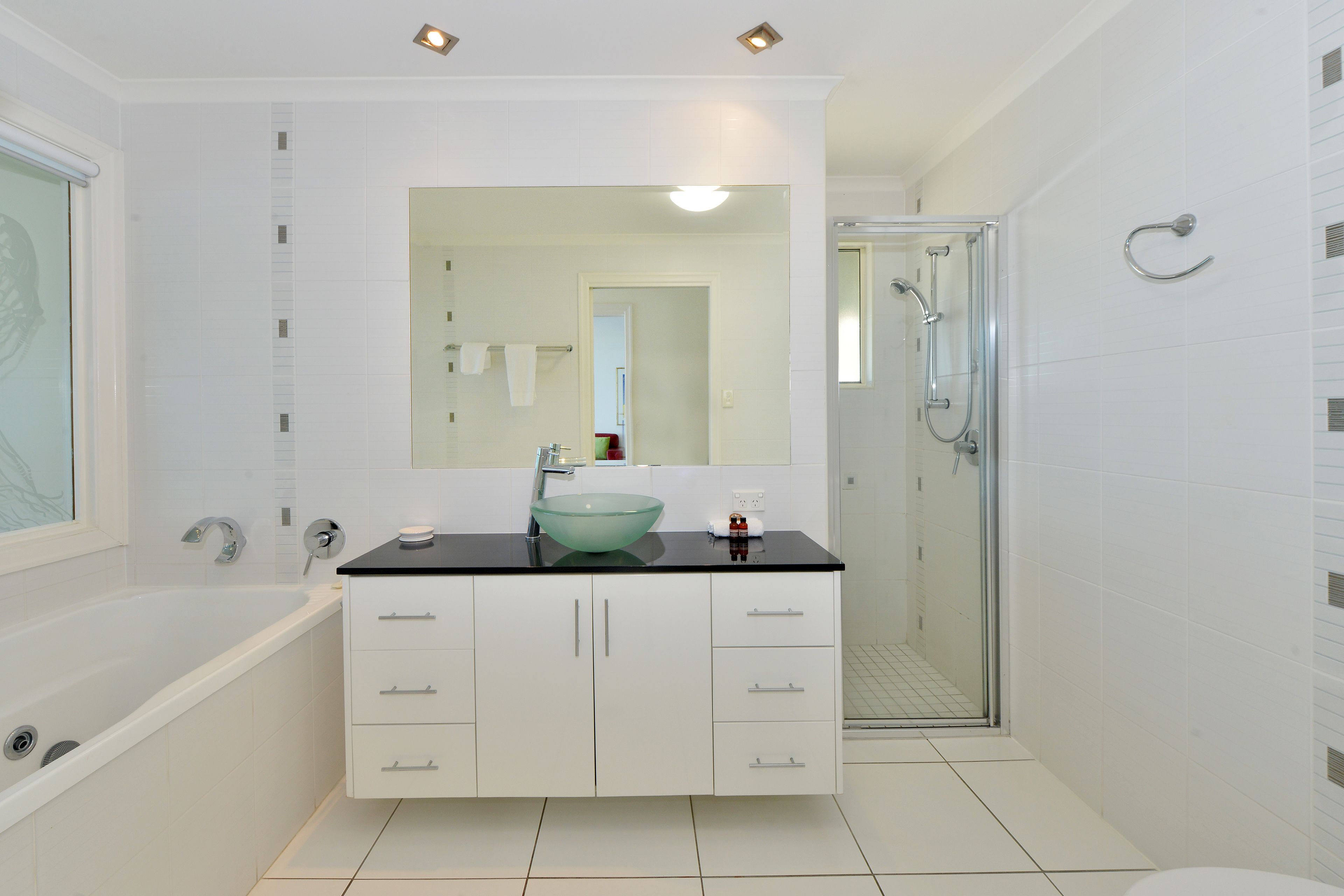 A modern bathroom with a glass-enclosed shower, a freestanding bathtub, and a large mirror above the sink.