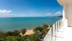 Un balcón con vistas despejadas al mar y la playa, rodeado de vegetación.