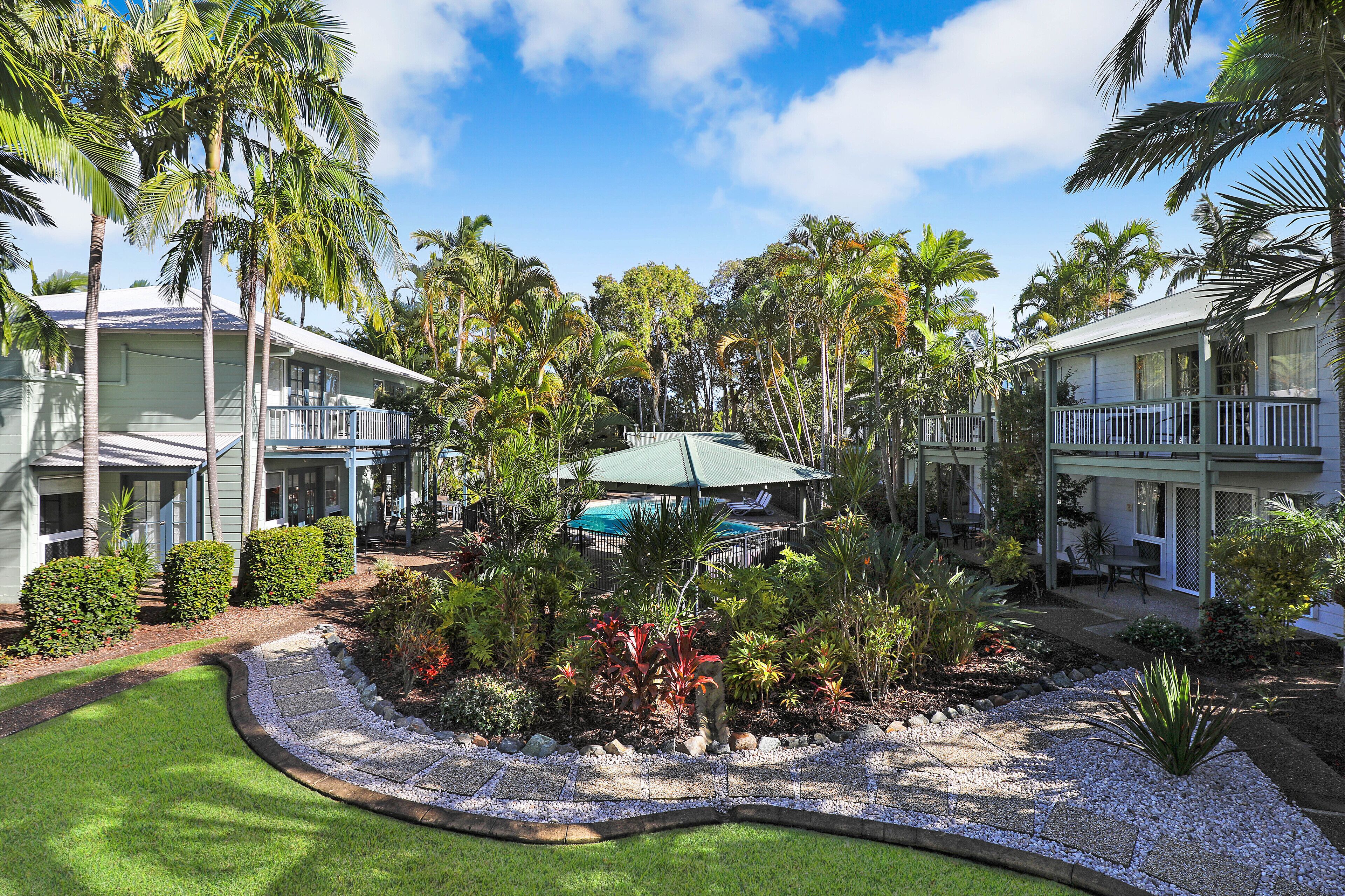 A resort with multiple buildings, a swimming pool, and lush tropical landscaping.