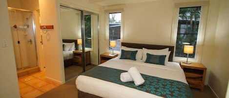 Un dormitorio de hotel con una cama grande, un vestidor y zona de ducha.