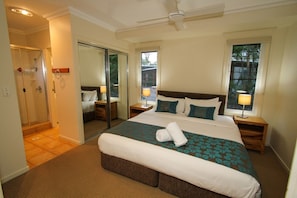 A hotel bedroom with a large bed, a walk-in closet, and a shower area.