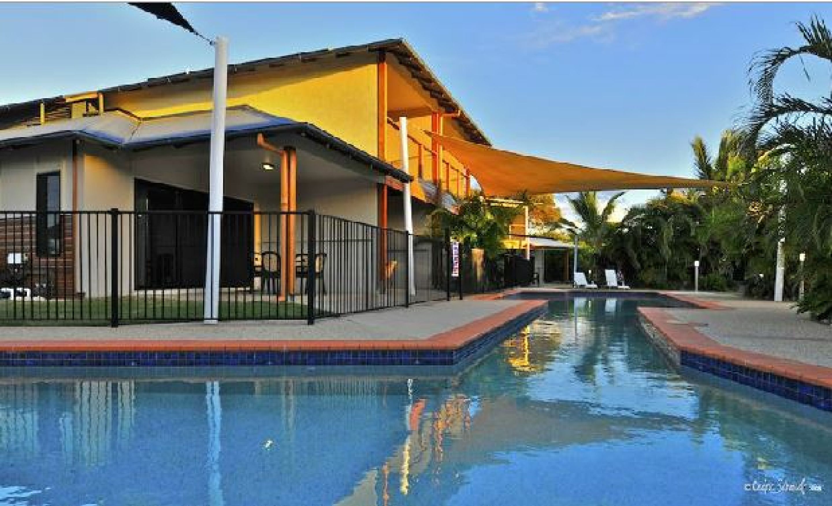 Un hotel con piscina, mobiliario exterior y un patio cubierto.