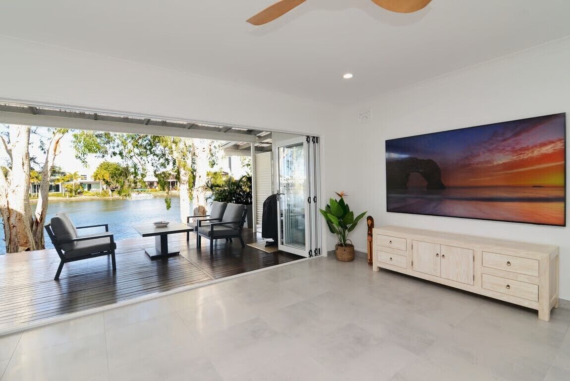 A modern living room with a view of a swimming pool, a ceiling fan, and a large painting.