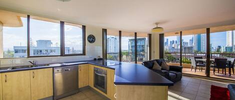 A modern kitchen with large windows, a dining area with a view, and a cityscape in the background.