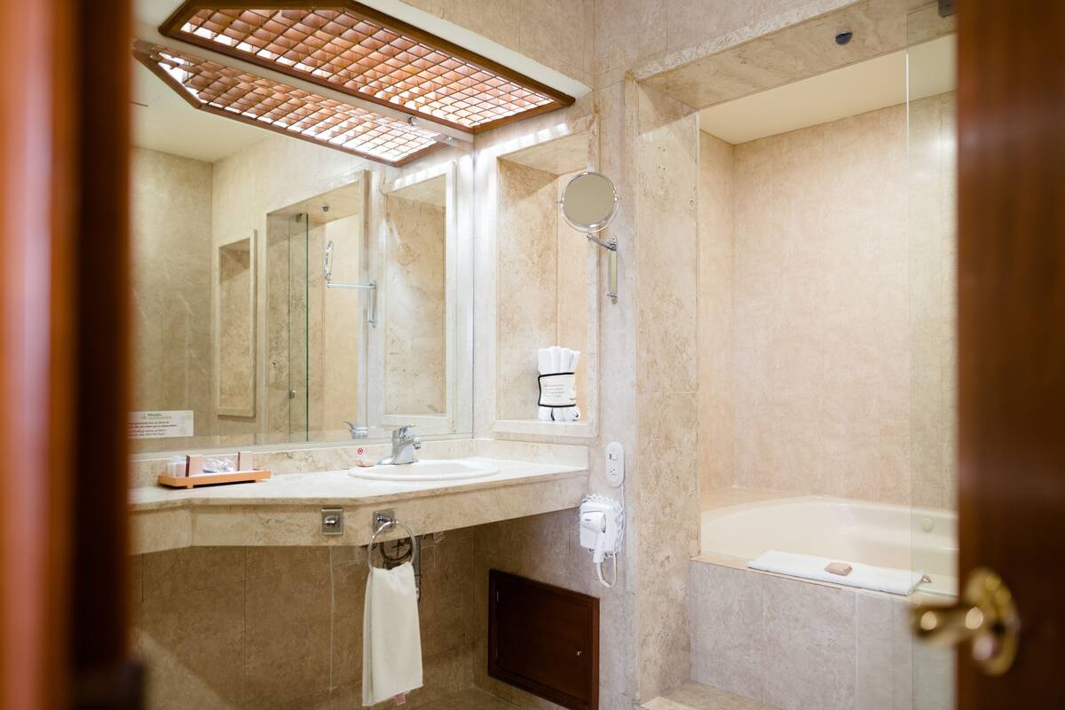 A modern bathroom with a large mirror, a sink, a shower, and a bathtub.