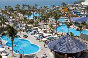 A resort with multiple swimming pools, palm trees, and a water slide. - LIVVO Lago Taurito Hotel & Aquapark All Inclusive (Mogan)