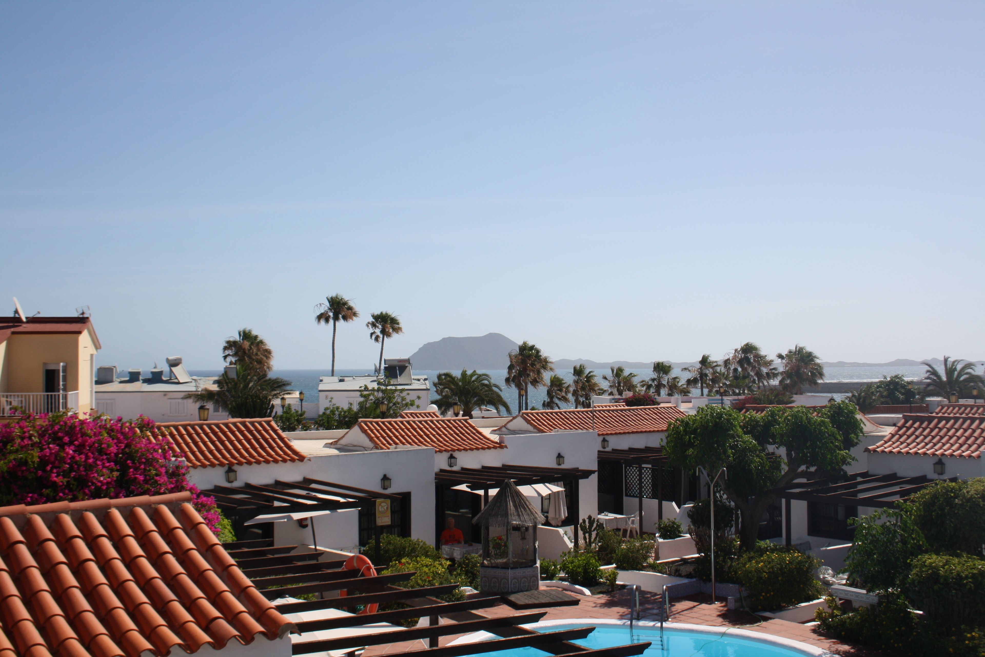 Un resort con piscina, mobiliario exterior y vistas al océano.