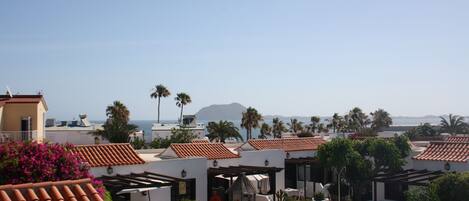A resort with a swimming pool, outdoor seating, and a view of the ocean.
