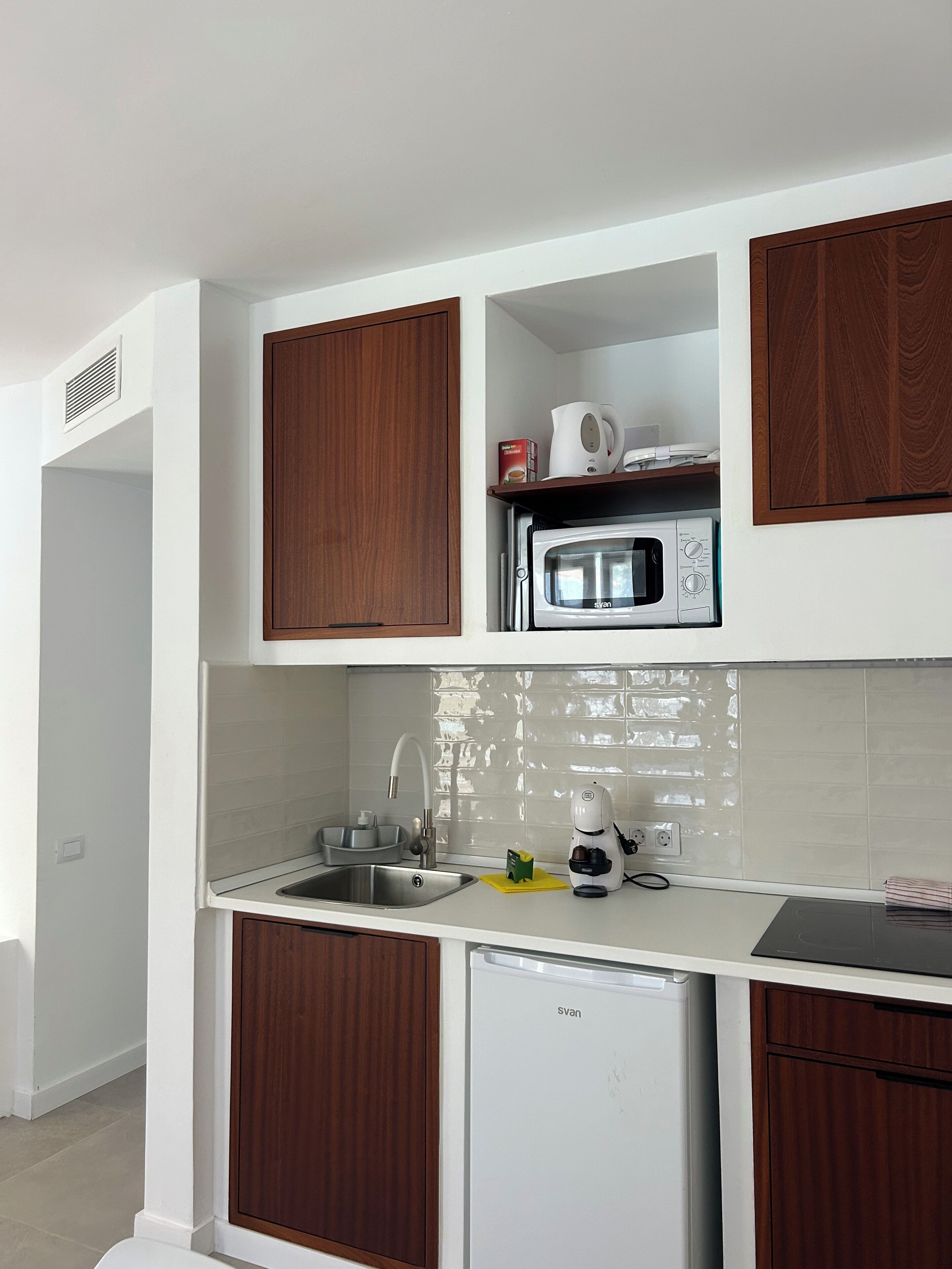 A modern kitchen with white cabinets, a microwave, a coffee maker, and a dishwasher.