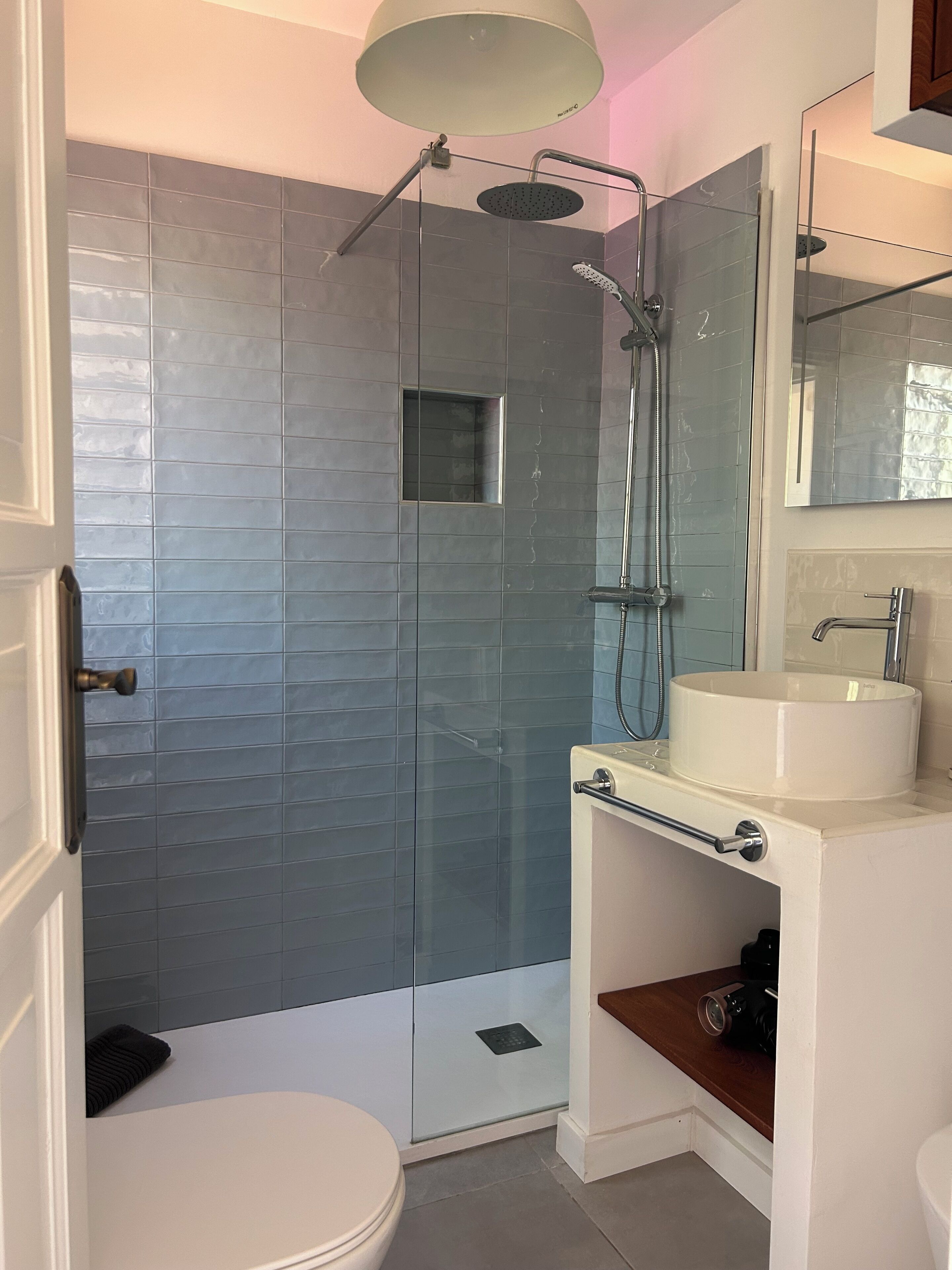 Une salle de bain avec une douche à parois de verre, un lavabo blanc et un miroir au-dessus du lavabo.