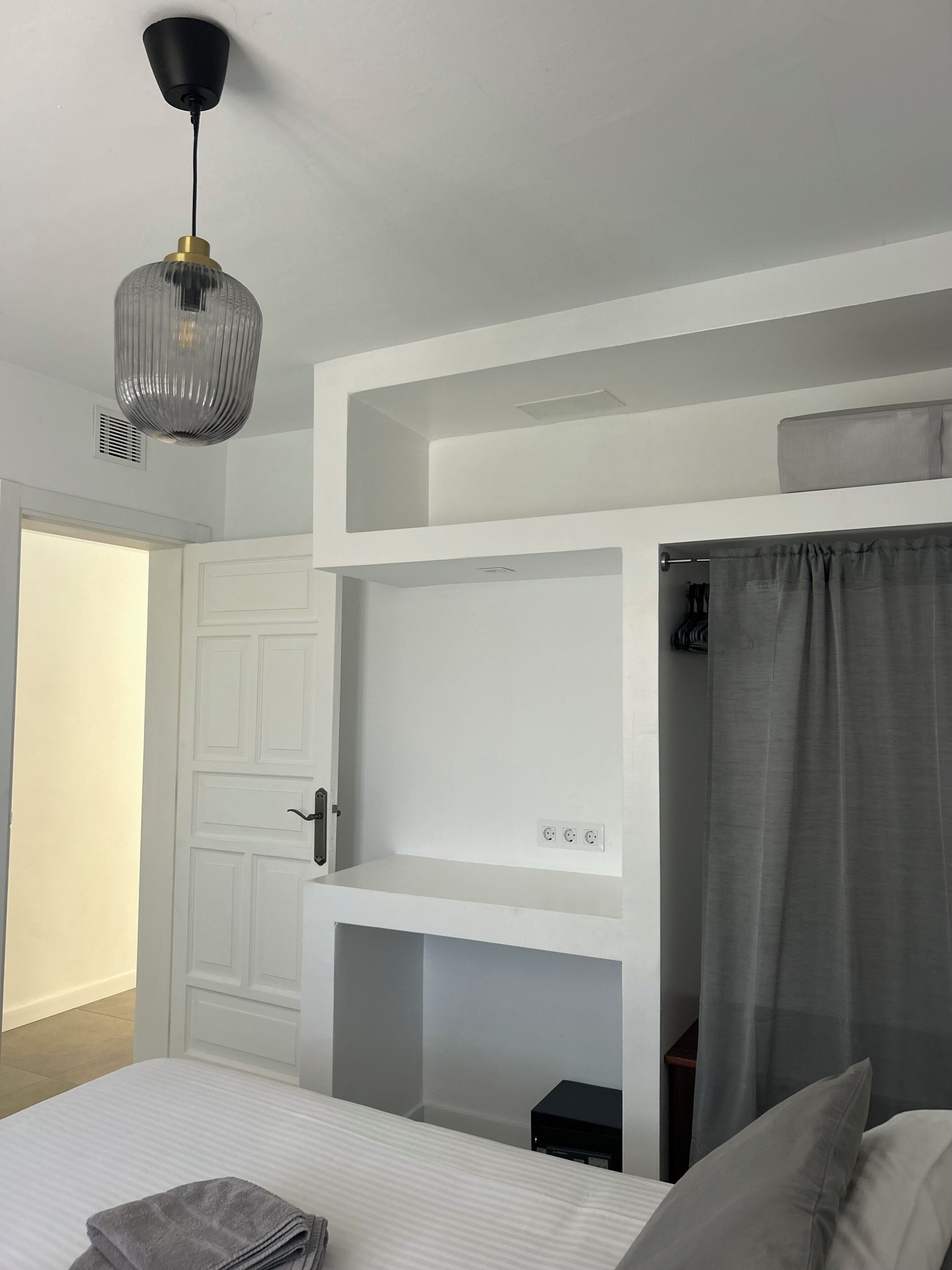 A bedroom with a bunk bed, a bedside table, a lamp, and a wardrobe.