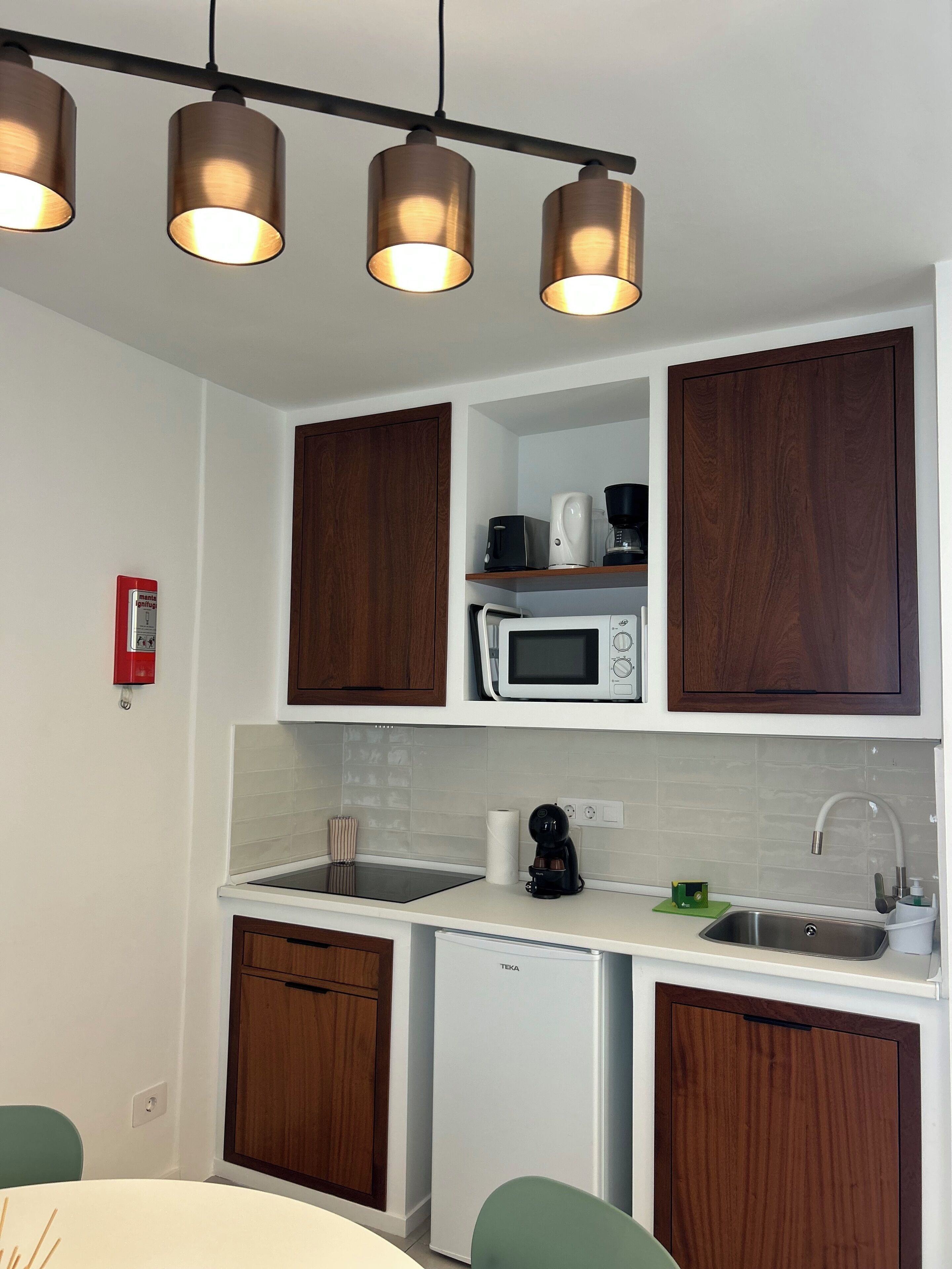 Una cocina moderna con armarios de madera, microondas, cafetera y lavaplatos.