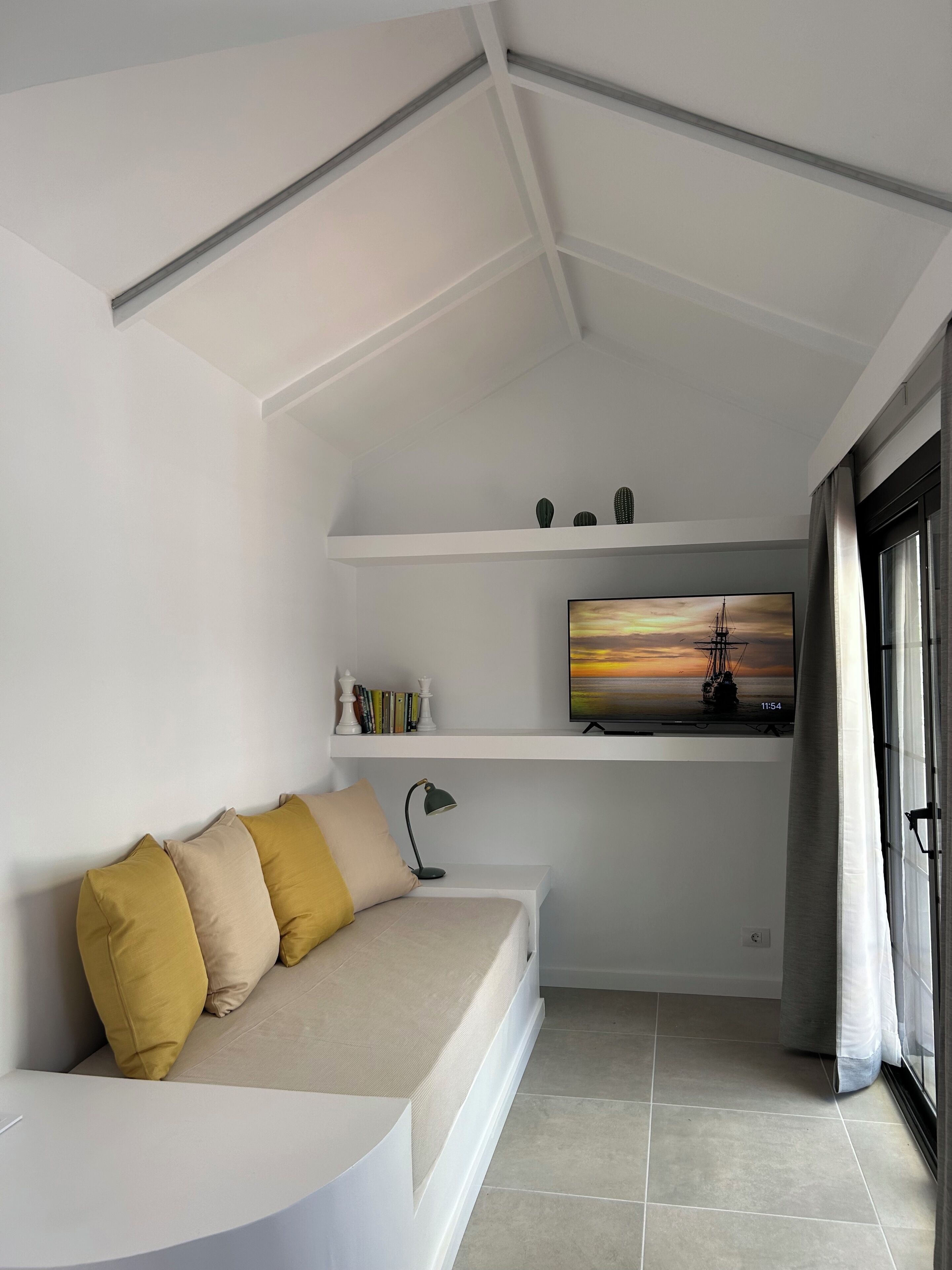 Una sala de estar moderna con un sofá blanco, un televisor de pantalla plana y una estantería.