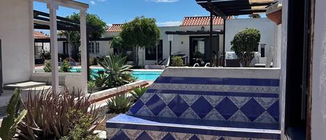 A patio with outdoor furniture, a pool, and a view of a residential area.