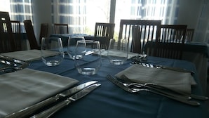 Une table à manger, dressée avec des couverts et des verres, entourée de chaises.
