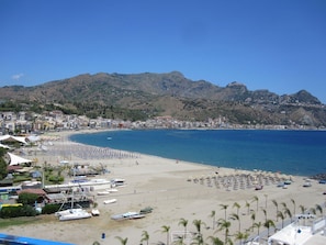 A coastal beach with a sandy shore, a row of beach umbrellas, and a clear blue sea. - Panoramic (Giardini Naxos)
