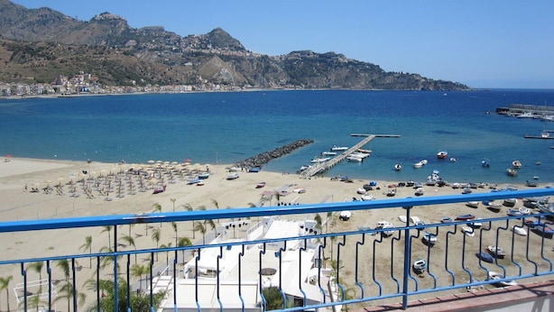 Une vue sur la plage, avec un ciel dégagé, une jetée et des bateaux.