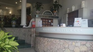 Un comptoir d’accueil à l’hôtel Panoramic, avec un mur en pierre et des colonnes.