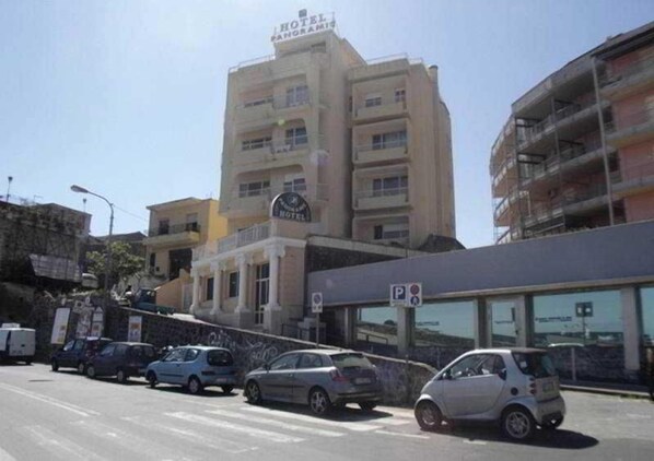 Un hôtel doté d’un parking, où plusieurs voitures sont garées, et un ciel dégagé.