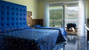 Une chambre d’hôtel avec deux lits, un balcon avec une table et une vue sur les montagnes.