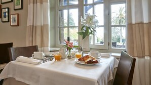 A breakfast table set with a plate of croissants, a pitcher of orange juice, and a vase with flowers. - El Jardín de Carrejo (Cabezon de la Sal)