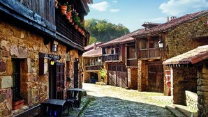 A cobblestone street lined with stone buildings featuring wooden balconies and traditional architecture. - El Jardín de Carrejo (Cabezon de la Sal)