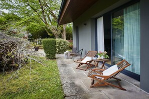 A patio with two wooden lounge chairs, a small table, and a potted plant. - El Jardín de Carrejo (Cabezon de la Sal)