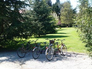 Bicycles parked on a gravel path in a park with trees and grass. - El Jardín de Carrejo (Cabezon de la Sal)