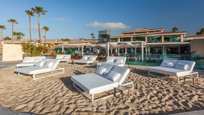 A beachside resort with white sun loungers, a pool, and a modern building with a red-tiled roof. - Kumara Serenoa by Lopesan Hotels (San Bartolomé de Tirajana)