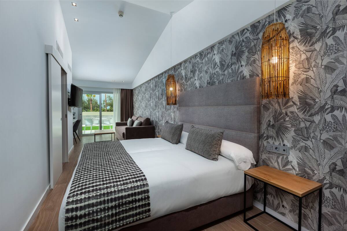Une chambre à coucher moderne avec un grand lit, une table de chevet et un luminaire fixé au mur.