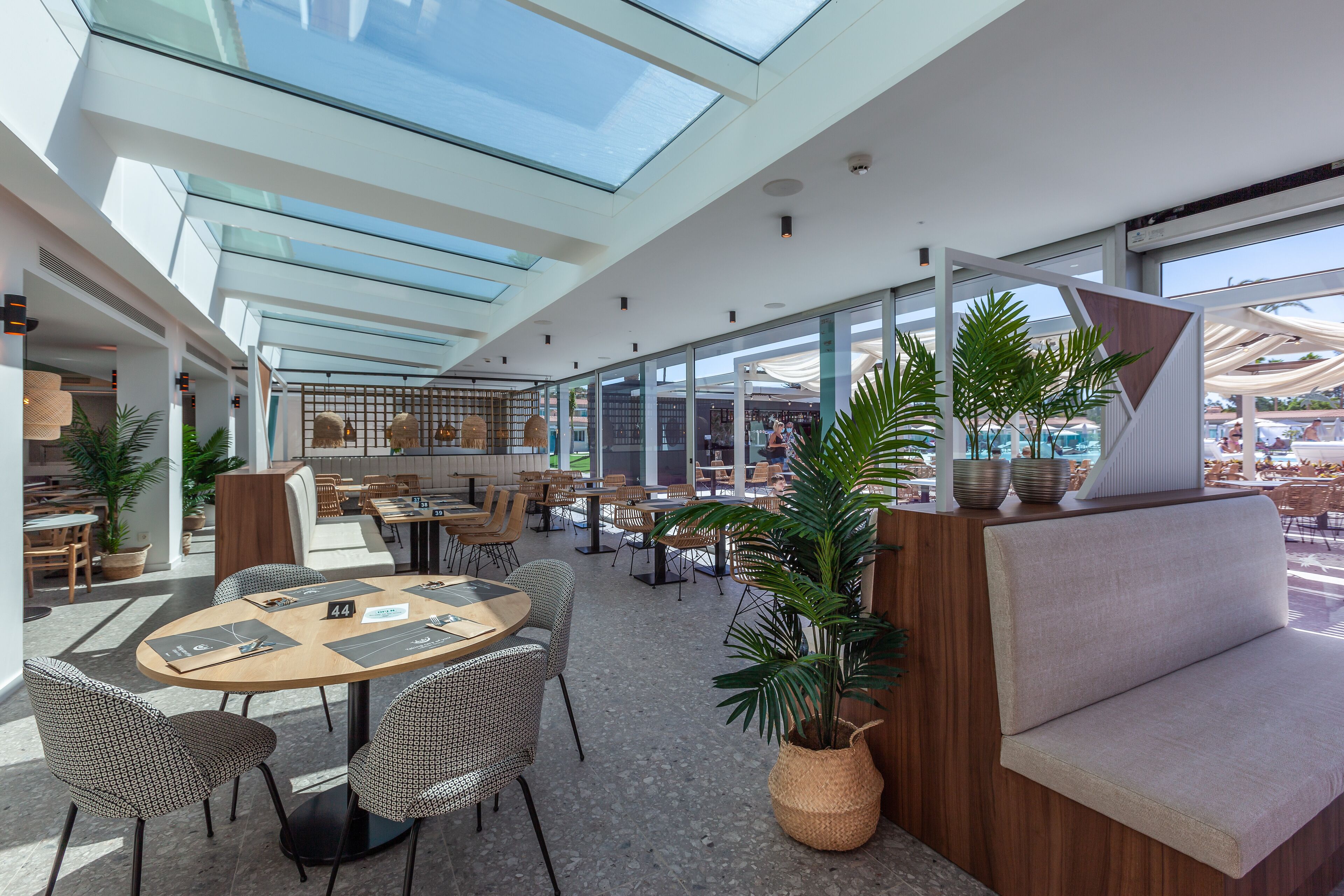 A spacious indoor area with high ceilings, glass walls, and a variety of seating arrangements including tables and chairs.