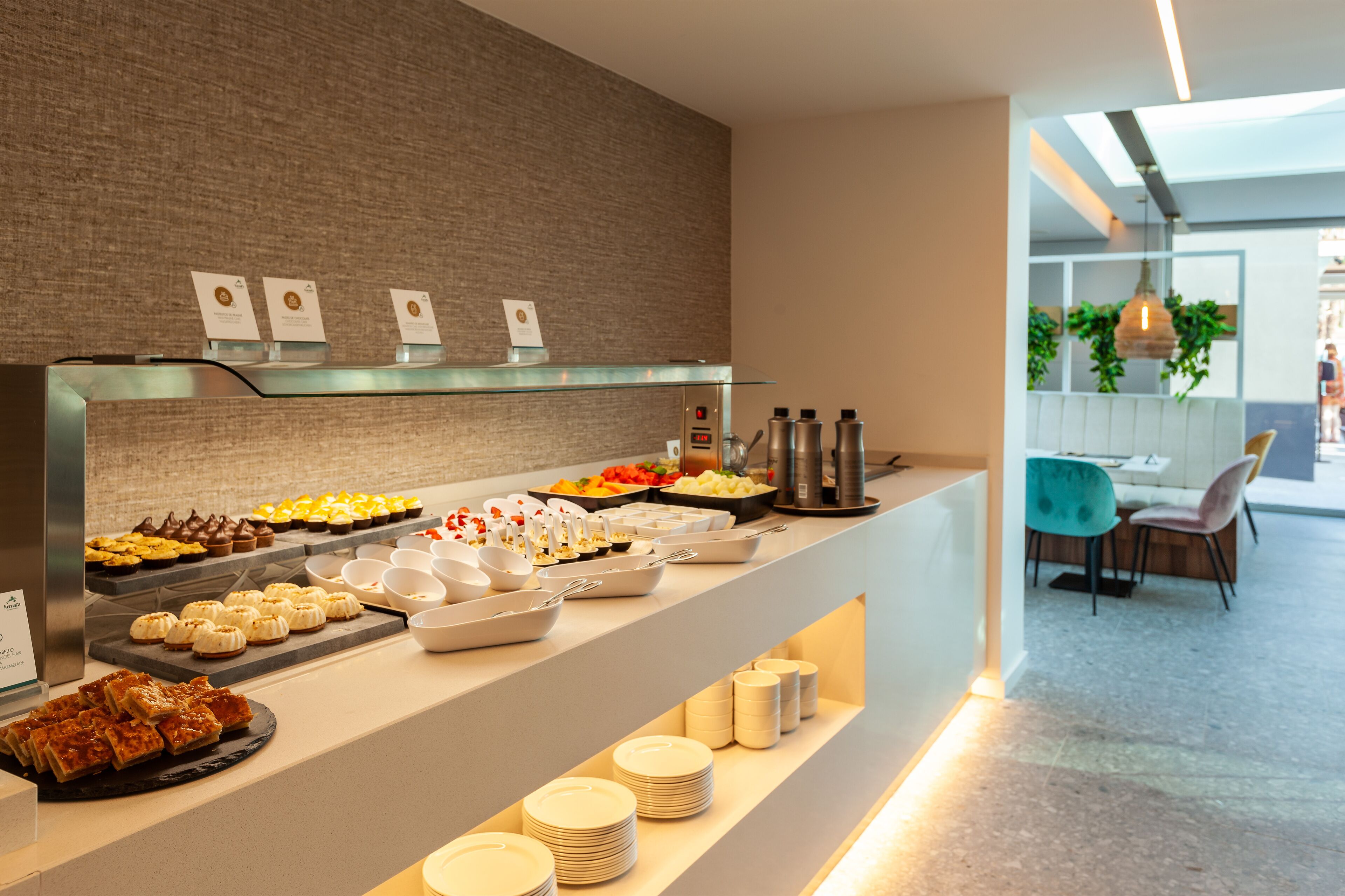 A buffet with various food items and a seating area with chairs and a table.