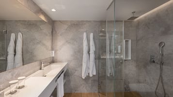 Een moderne badkamer met een douchecabine van glas, een grote spiegel en een wit badkamermeubel met een wastafel en handdoekhouder.