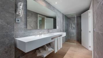 Un baño moderno con un espejo grande, dos lavamanos y una zona de ducha.