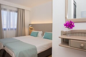 A hotel room with a bed, a bedside table with a vase of flowers, and a mirror above the table. - Los Tulipanes (Tias)