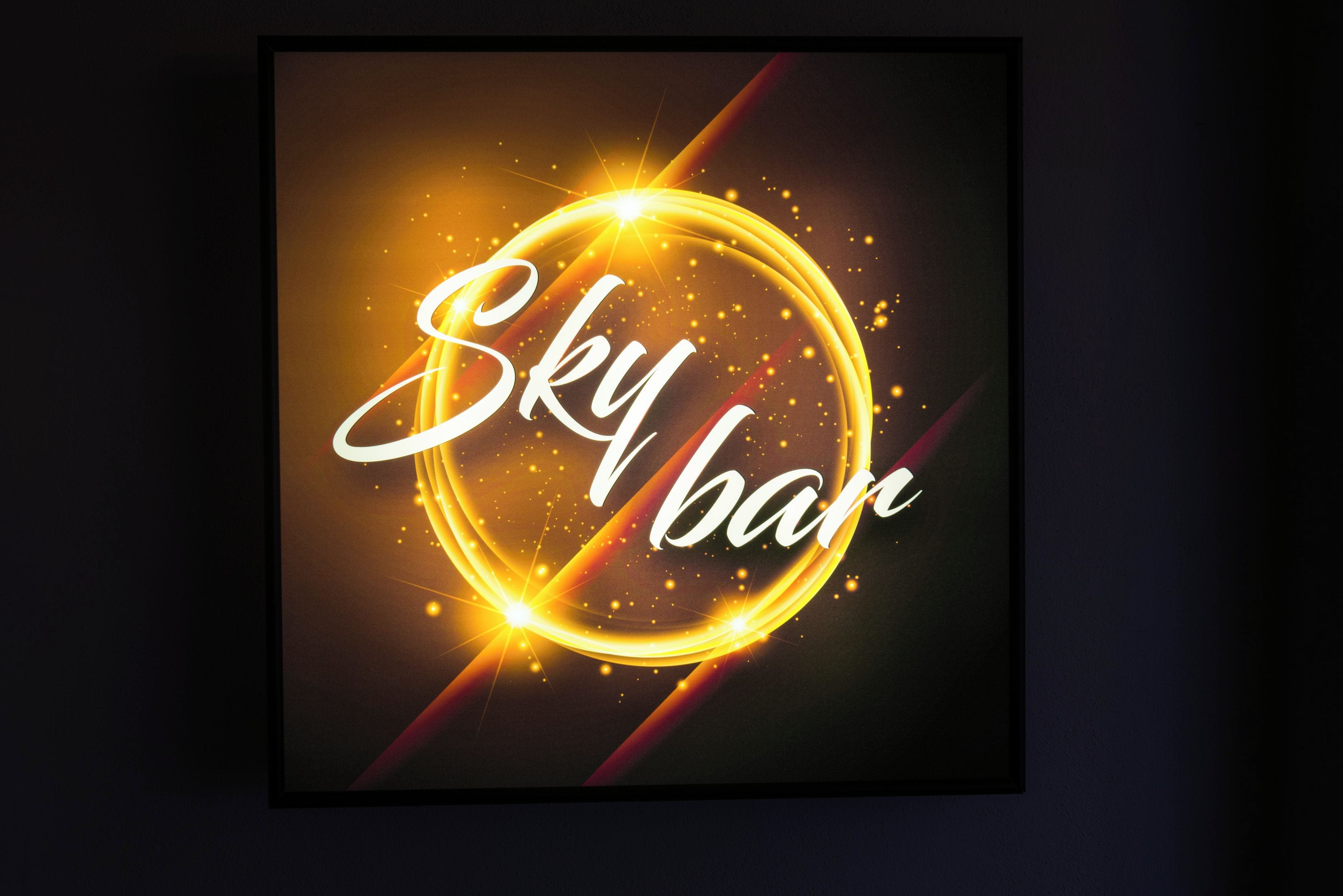 Una obra de arte en marco con el texto "Sky bar" y un diseño circular brillante.