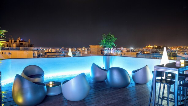 Un bar en la azotea con asientos modernos y una piscina.