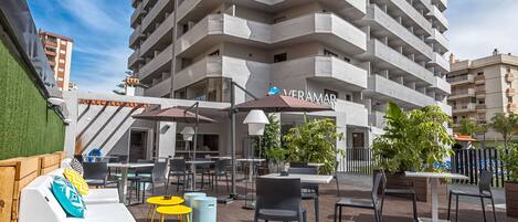 Um hotel moderno com terraço, mobiliário de exterior e zona de piscina.