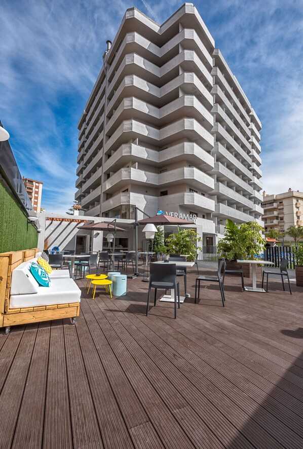 A modern hotel with a terrace featuring outdoor seating and a pool area.