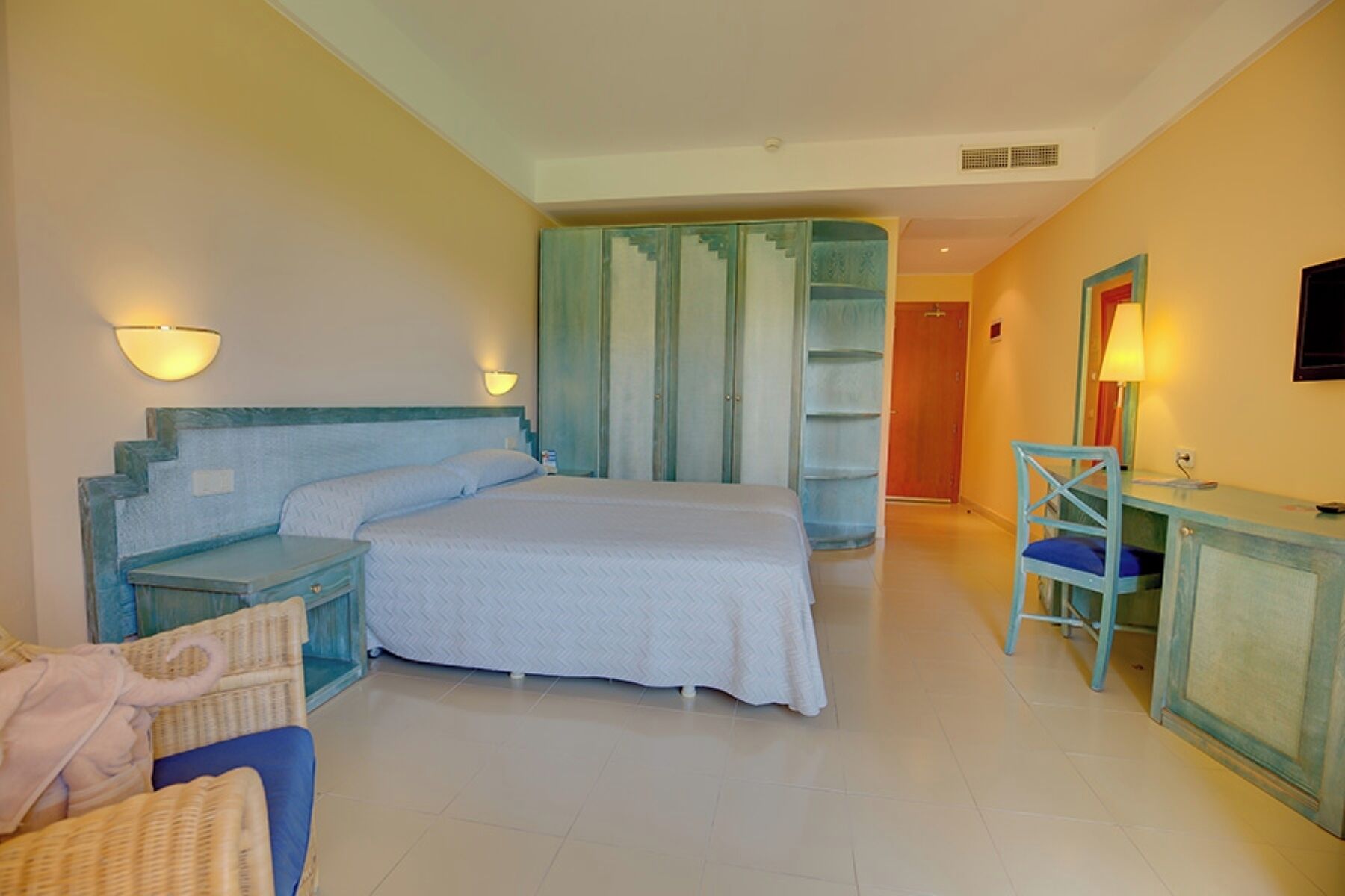 Une chambre à coucher comprenant un lit, des tables de chevet, une chaise, un bureau et une armoire.