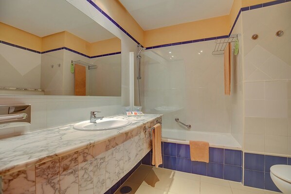 Une salle de bain avec un lavabo en marbre, une baignoire et une douche.