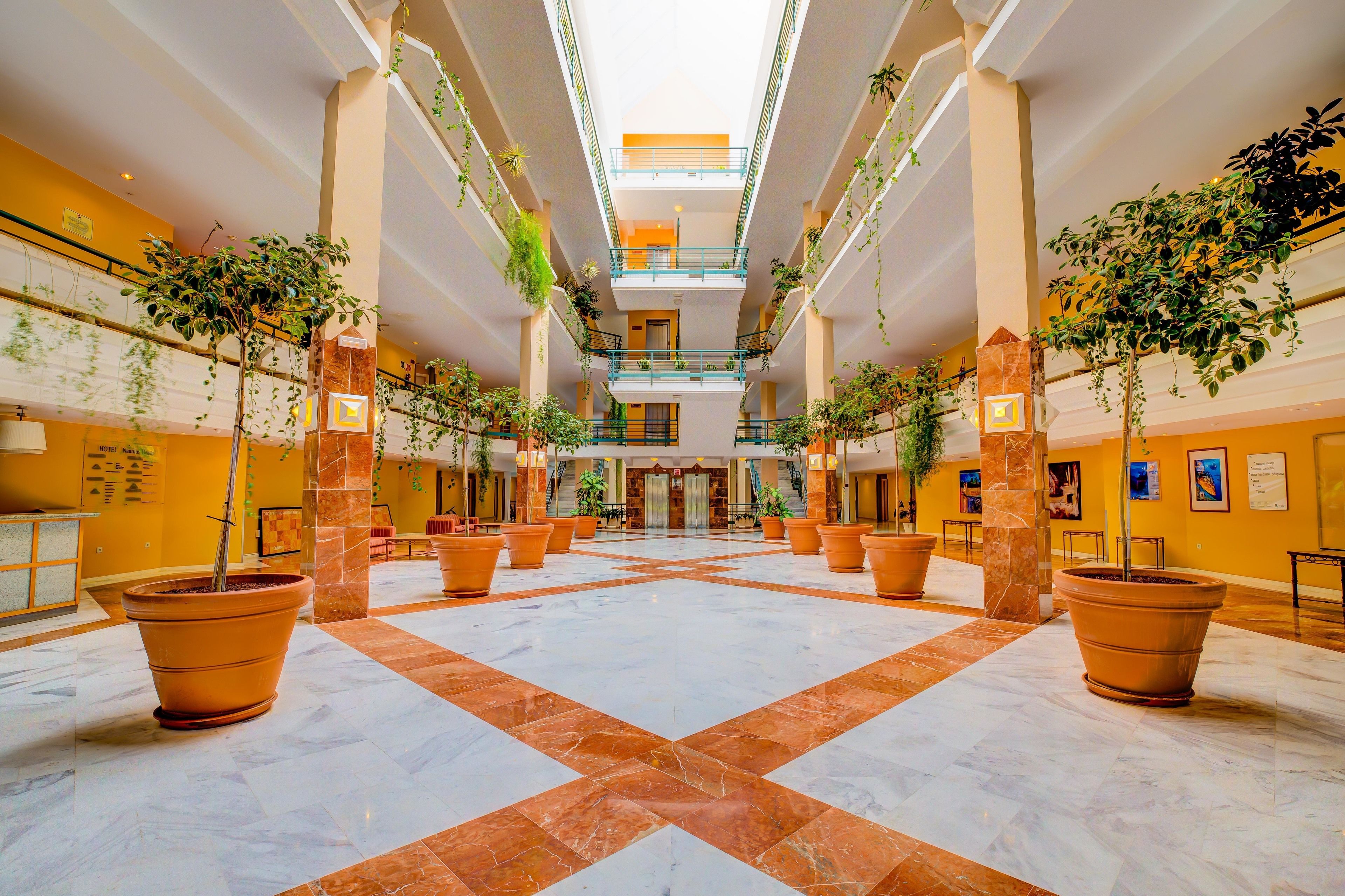 Een ruime atrium met een hoge plafond, meerdere verdiepingen en grote potplanten.