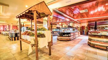 A spacious hotel lobby with a central food display, wooden ceiling, and tiled flooring.