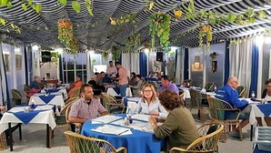 Ein Restaurant mit Tischen, die mit blauen Tischdecken bedeckt sind, umgeben von Korbstühlen.