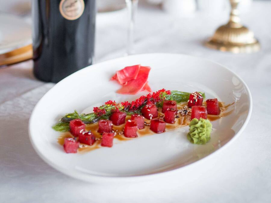 A dining table with a bottle of wine, a glass, and a plate of food.