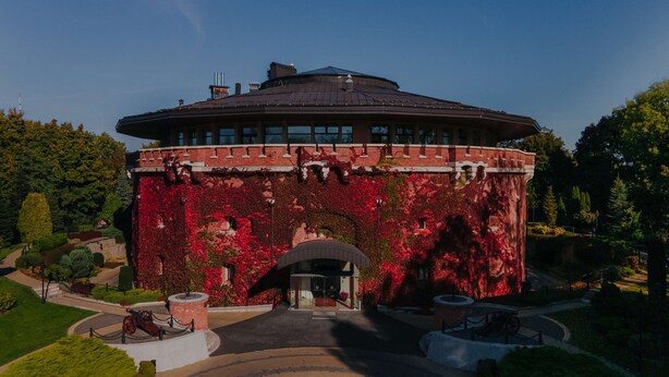Een gebouw met een rond dak en bakstenen muren bedekt met rood herfstblad.