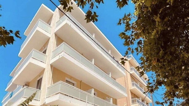 A multi-story building with balconies, a covered outdoor seating area, and a clear sky. - International Hotel (Rhodes)